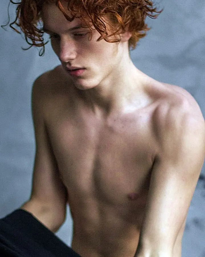 Homme torse nu, en sous-vêtements, debout près d'une fenêtre, regardant vers l'appareil photo, dans une ambiance naturelle et douce.