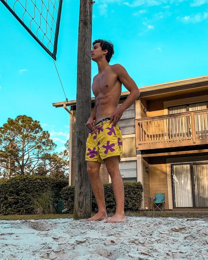 Homme torse nu, en sous-vêtements, debout près d'une fenêtre, regardant vers l'appareil photo, dans une ambiance naturelle et douce.