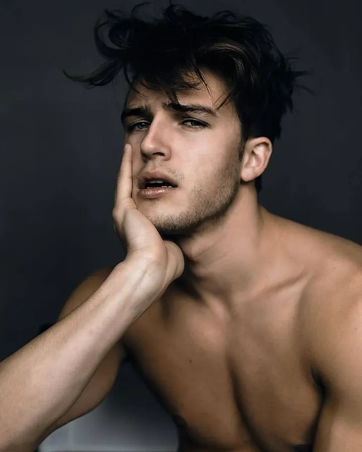 Homme torse nu, regardant l’appareil, main dans les cheveux, ceinture noire, jeans