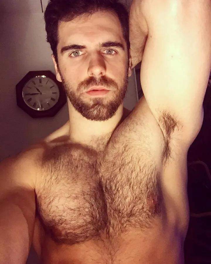 Homme torse nu, barbe, regardant l’appareil, horloge murale en arrière-plan