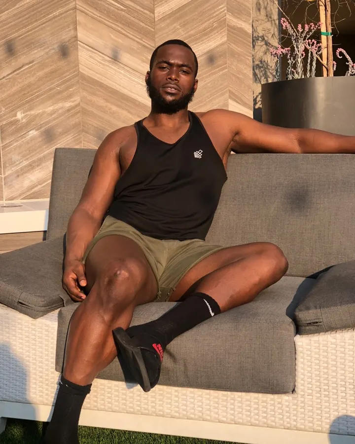 Homme torse nu, en sous-vêtements, regard intense contre un fond gris.