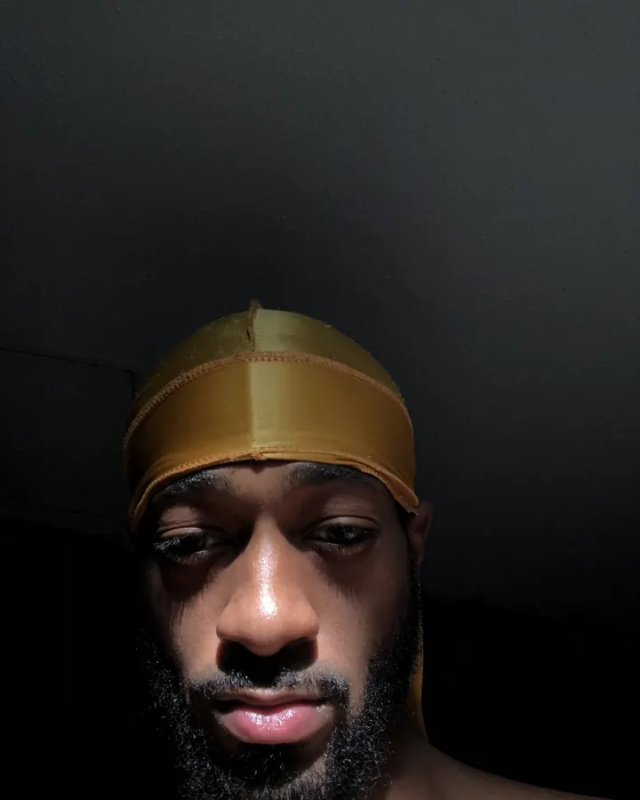 Homme africain de 25 à 35 ans, torse nu, portant un t-shirt blanc, sous-vêtement Calvin Klein, devant un rideau jaune.