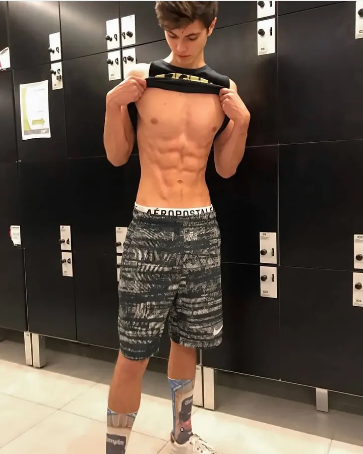 Homme torse nu, debout, regardant directement l'appareil photo, avec une main sur la hanche.
